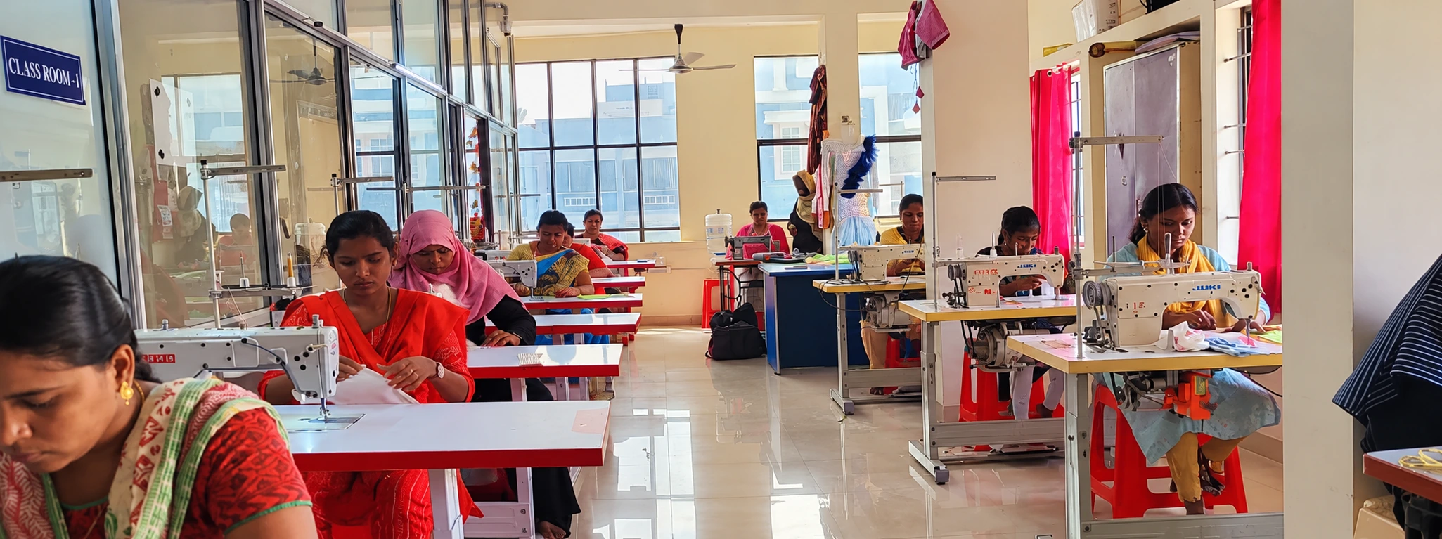 Row of sewing machines in the Shanas tailoring lab with students stitching garments